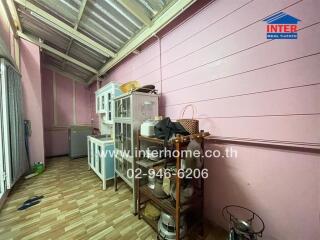 Indoor kitchen area with wooden and metal storage shelves, glass cabinet, and refrigerator.