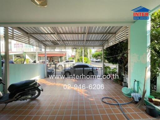 Covered outdoor area with tiled flooring and garden hose