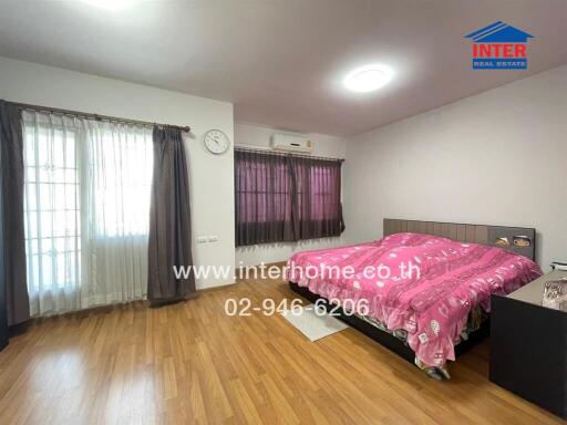 Bright bedroom with wooden flooring and large windows