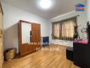 A bedroom with wooden floor, a window with curtains, and a wooden wardrobe.