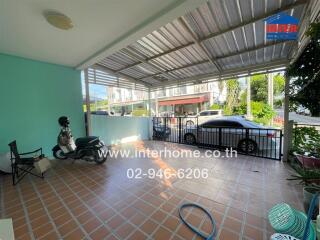 covered outdoor area with tiled floor, parked scooter and car