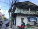 Exterior view of a two-story building along a street with parked motorbikes