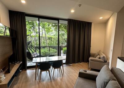 A cozy living area with large windows, showcasing a lush view of the garden.