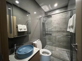 Modern bathroom with a glass shower, toilet, sink, and mirror