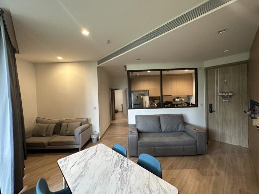 Modern open-plan living room and kitchen with grey furniture and a marble dining table