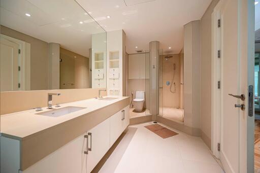 Modern bathroom with dual sinks, large mirror, and spacious shower area