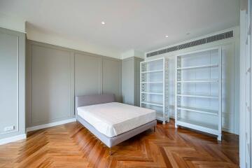 Spacious modern bedroom with wooden floor and empty bookcases