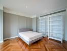 Spacious modern bedroom with wooden floor and empty bookcases