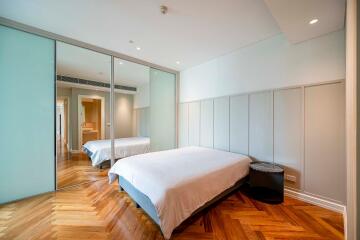 Modern bedroom with large mirrored wardrobe and wooden flooring