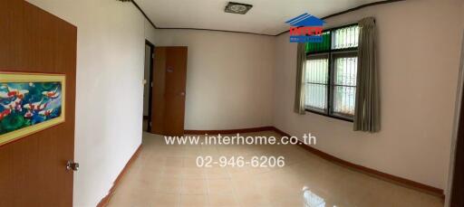 A bedroom with tiled floor, a window with curtains, and a door featuring a decorative painting.