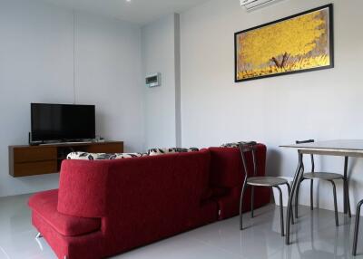 Living room with red sofa, wall-mounted TV, dining table and chairs