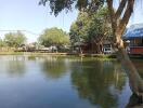 View of a serene pond surrounded by trees and small structures