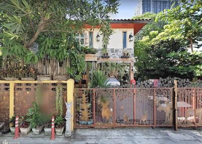 Front view of a two-story house with a garden and a gated fence