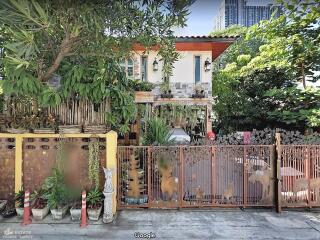 Front view of a two-story house with a garden and a gated fence