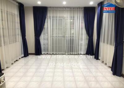 Empty living room with tiled floor and large windows covered by blue curtains