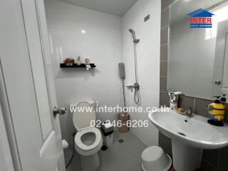 Modern bathroom with white tiles, a hanging shelf, and essential fixtures