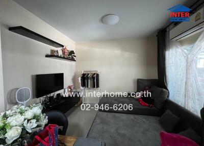 Living room with couch, TV, shelves, and air conditioning unit