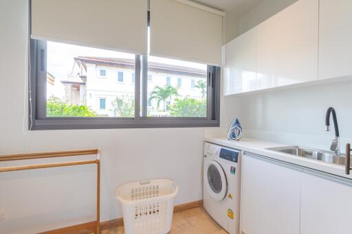 Laundry room with sink, washing machine and a window.