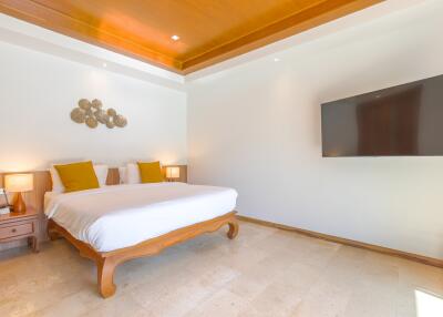 Modern bedroom with a wooden bed frame, wall-mounted TV, and large bed with yellow pillows