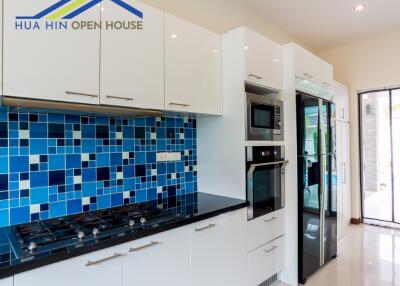 Modern kitchen with white cabinets, blue mosaic backsplash, and stainless steel appliances