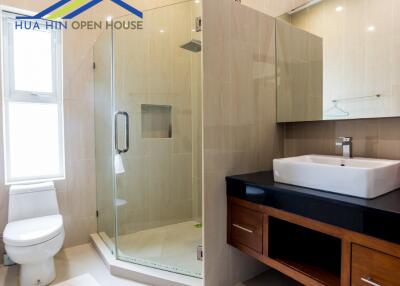 Modern bathroom with glass shower, toilet, and vanity with sink