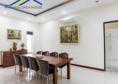 Dining room with a wooden table and chairs, wall paintings, air conditioning unit, and access to kitchen