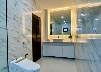 Modern bathroom with sleek marble surfaces and illuminated mirror