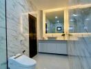 Modern bathroom with sleek marble surfaces and illuminated mirror