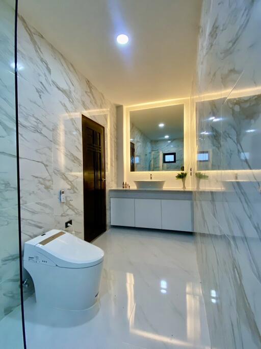 Modern bathroom with sleek marble surfaces and illuminated mirror