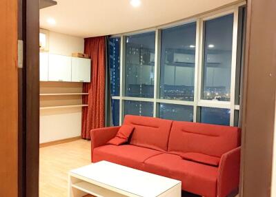 Modern living room with red sofa, large window, and wooden flooring