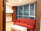 Modern living room with red sofa, large window, and wooden flooring