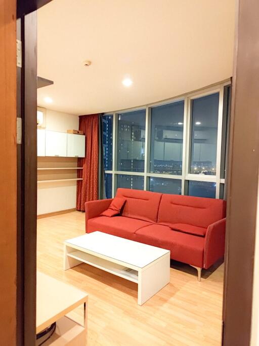 Modern living room with red sofa, large window, and wooden flooring