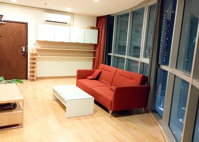 Modern living room with a red sofa, coffee table, wooden flooring, and large windows