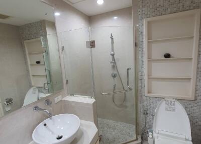 Modern bathroom with glass shower enclosure, sink, and toilet