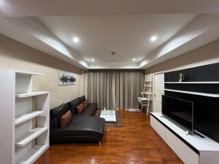 Modern living room with brown parquet floor, sectional leather sofa, TV unit, and sleek shelving