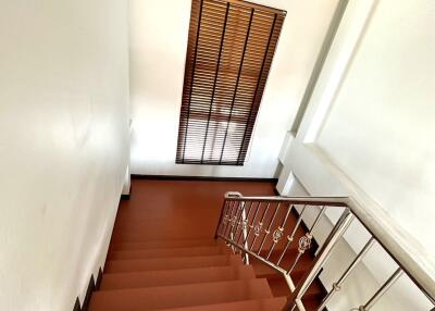 Wooden stairs with metal railing and window with blinds