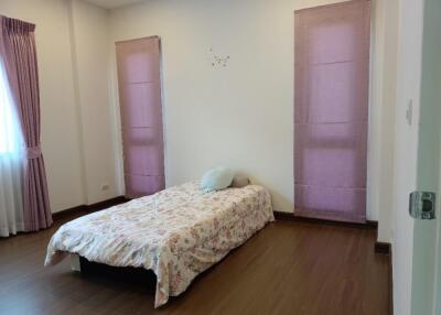 Bedroom with single bed, two tall windows, and hardwood flooring