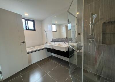 Modern bathroom with dual sinks, a large bathtub, and a shower