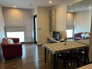 Modern living room with dining area, red sofas, and large mirrored wall