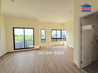 Bright and spacious living area with large windows, balcony access, and wood flooring