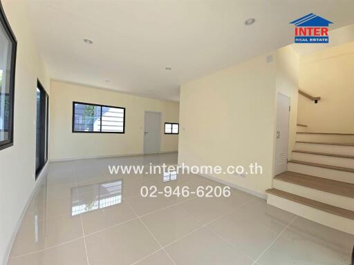 Spacious modern living area with tiled flooring and staircase