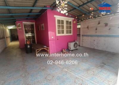 Covered outdoor space with a small pink building and decorative lights