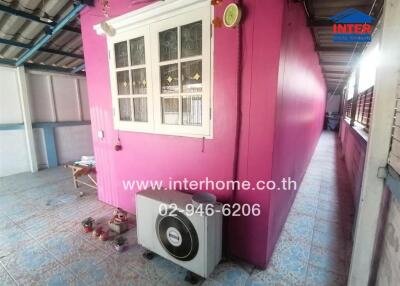 Outdoor area with vibrant pink wall and ventilation unit