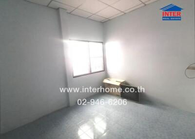 Empty bedroom with tiled floor, a small window, a cabinet, and sunlight streaming in