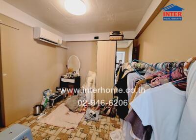 Cluttered bedroom with personal items and a wall-mounted air conditioner