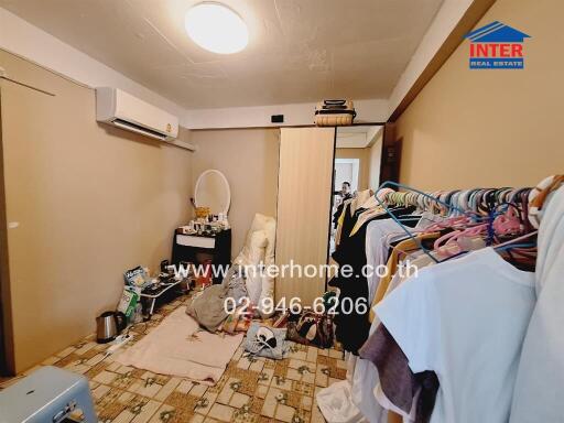 Cluttered bedroom with personal items and a wall-mounted air conditioner