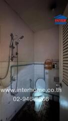 Bathroom with toilet, shower, and tiled walls.