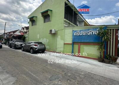 Street view of residential building with visible signage and parked cars