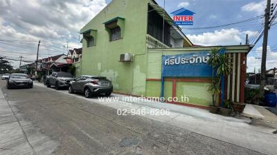 Street view of residential building with visible signage and parked cars