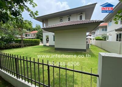 Exterior view of a house with a green lawn and surrounding fence